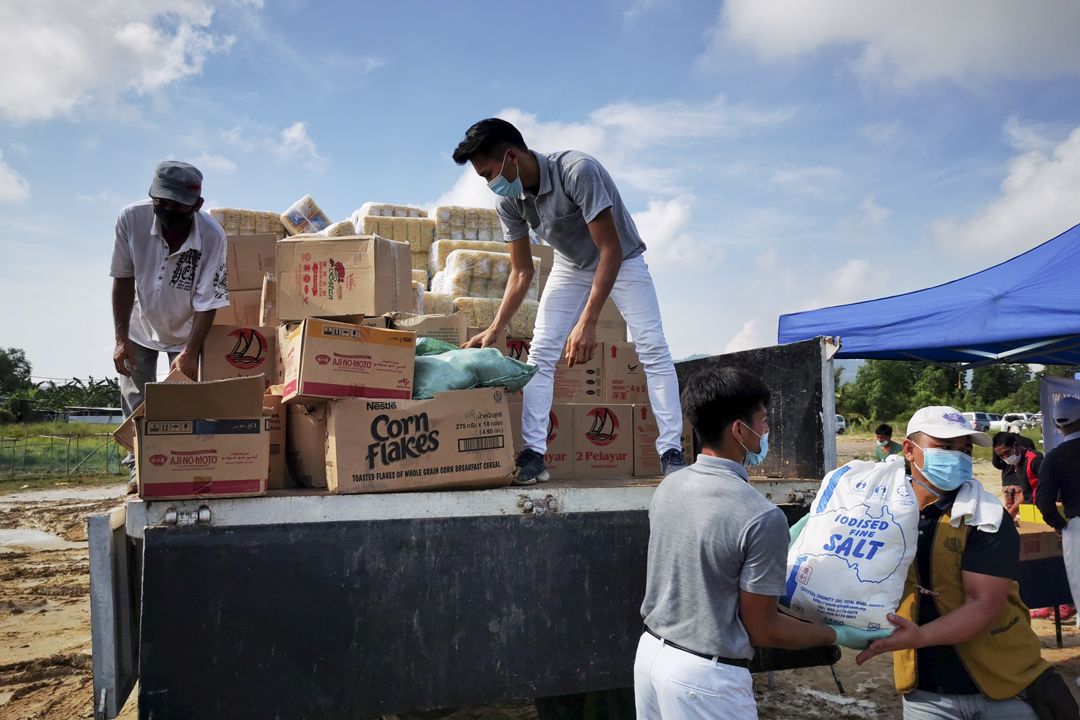 山打根志工於甘榜曼嘉利奧阿讓發放物資予無國籍外勞。【攝影：黃守芬】