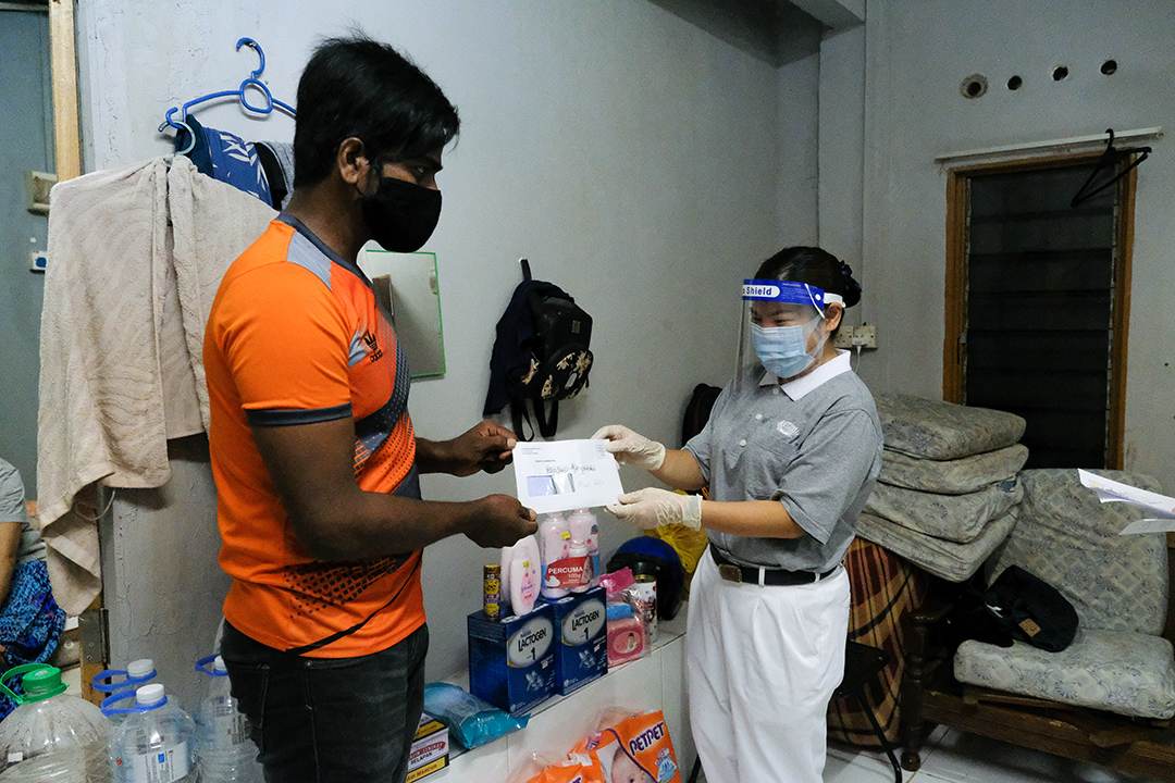 志工俞小氛（右）做足防疫措施，在社交距离下，将慈济的补助金交给缅甸籍难民拉菲克。 【摄影：林振胜】