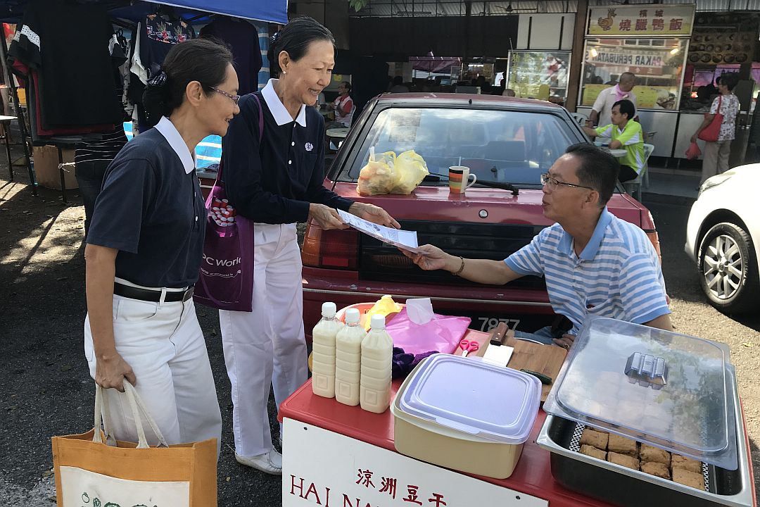  Tzu Chi volunteers Chiew Lee Hoon (left) and Boon Yok Wah delivered blessings and promoted environmental protection along Bukit Baru street. [Photograph by Tai Piang Boon]