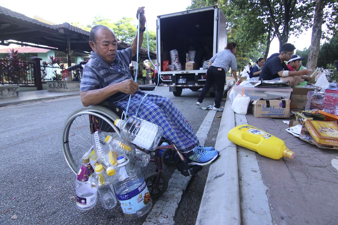Chong Ngoi Lee is physically disabled, but not disabled at heart. He feels immense joy being able to help tie up plastic bottles with strings. [Photograph by Yong Mun Fei]