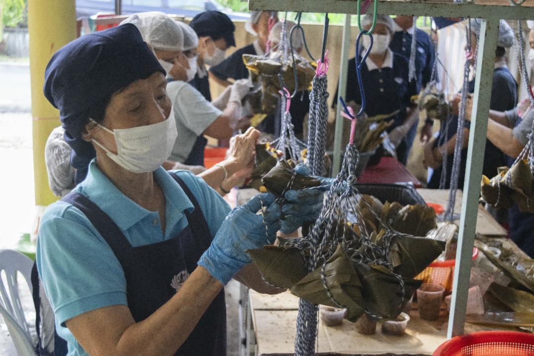 来自淡属百乐县直凉的慈济志工与大众，在欢庆端午佳节之际，首次主办裹素粽义卖活动，借着社区的力量，将爱心化为行动，传送至沙巴州山打根灾区。 【摄影：张国樑】