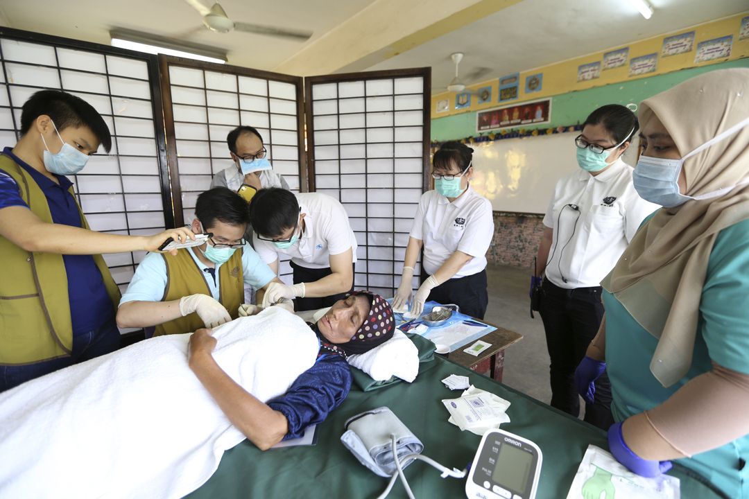 慈济人医会志工在课室架设临时手术台，为朱喜拉切除右臂的脂肪瘤。 【摄影：梁倩宜】